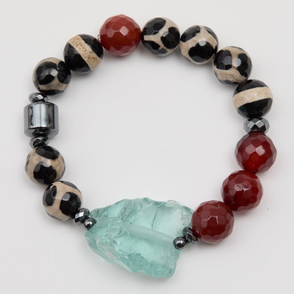 Beaded bracelet with red, black, and white beads and a large green stone on a white background