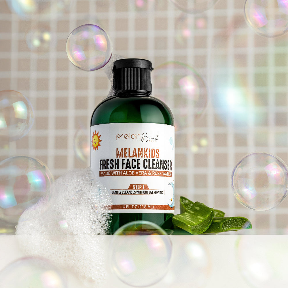 Bottle of Melankids Fresh Face Cleanser with bubbles and aloe vera leaves on a textured background