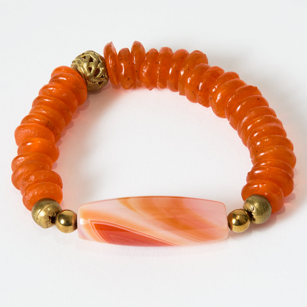 Bracelet with orange beads and an orange and white stone on a white background