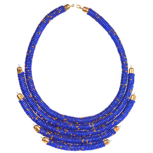 A woman wearing a beaded necklace with gold-tone accents and a wide hook for closure.