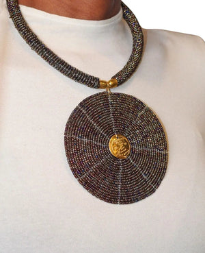 A model wearing a circular black beaded necklace with gold accents.