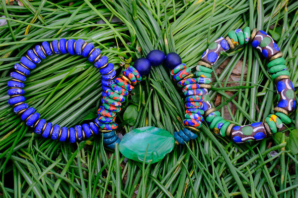 Three colorful beaded bracelets on a bed of green leaves