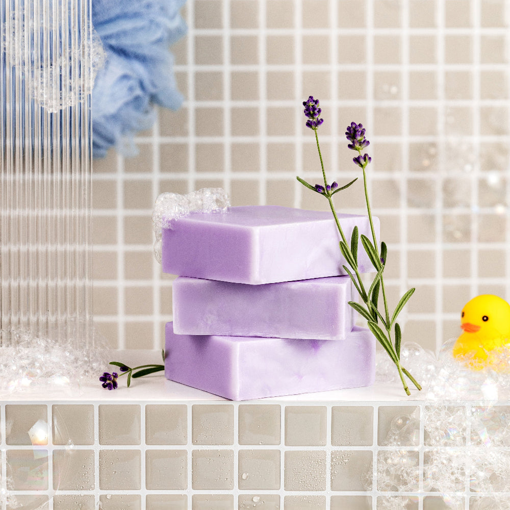 Lavender Soap bars with lavender flowers on a tiled bathroom shelf.