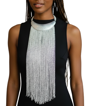 Woman wearing a long, beaded necklace with a plain background