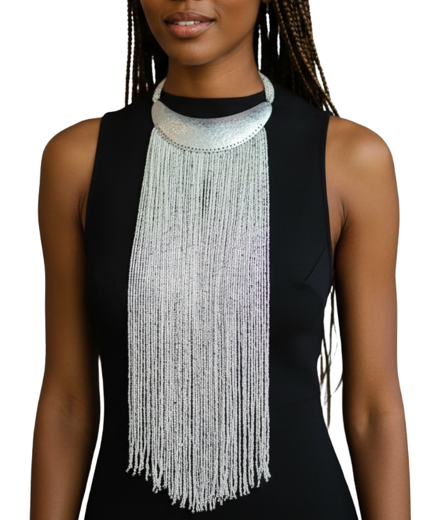 Woman wearing a long, beaded necklace with a plain background