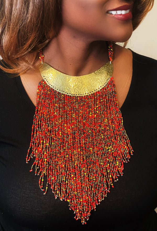 A woman wearing a red and gold beaded necklace.