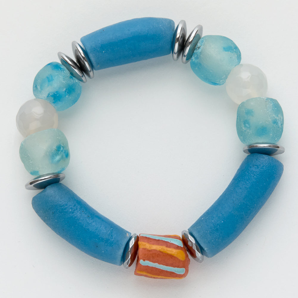 Blue and white beaded bracelet with a orange and blue striped accent bead on a white background
