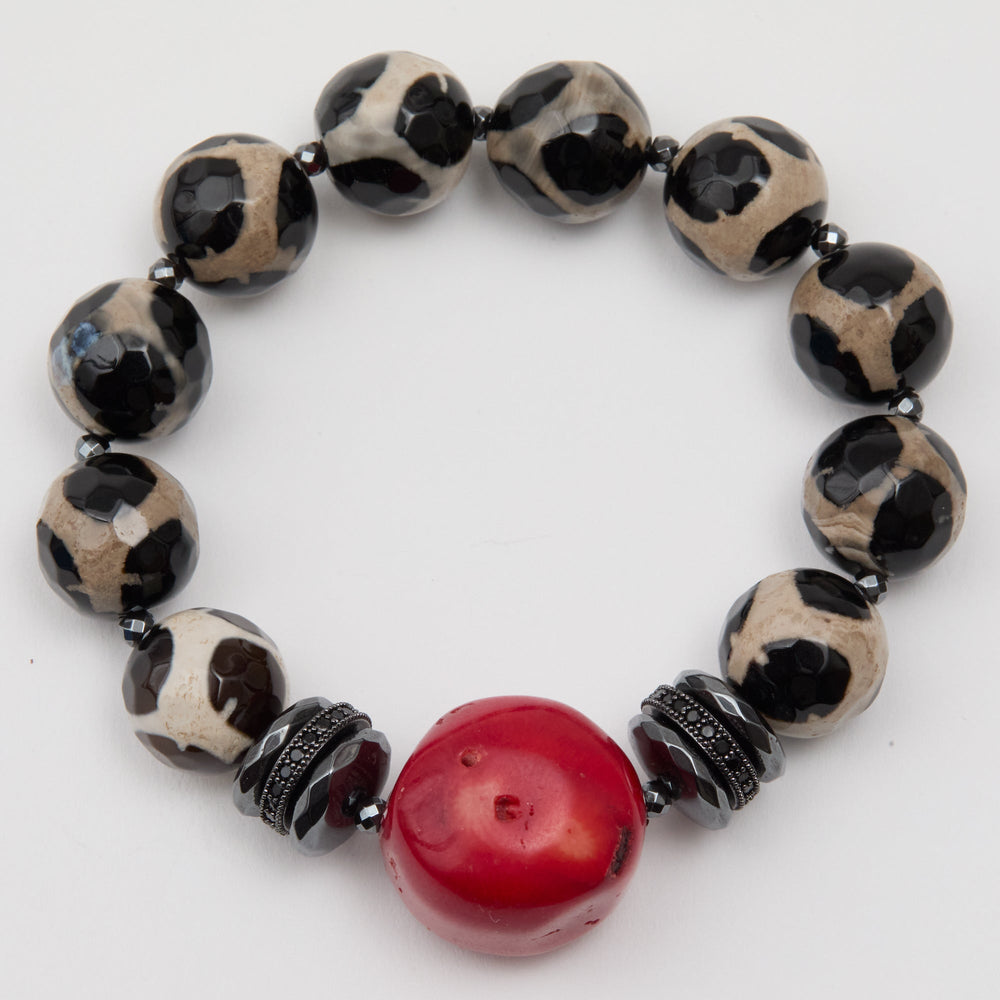 Bracelet with black and white patterned beads and a red central bead on a white background