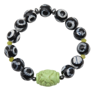 Black and white beaded bracelet with a green carved bead on a white background