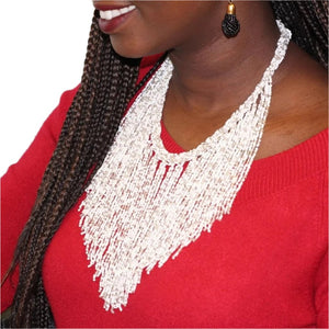 A woman wearing a white beaded necklace paired with some black beaded earrings.