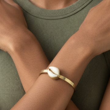 Woman wearing a brass bracelet on a neutral background