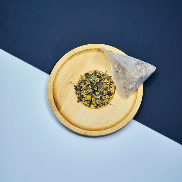 Smooth September, A natural herbal arrangement featuring dandelion leaf, fresh ginger root, nettle leaves, chamomile flowers, and dried burdock root on a half white & black surface. 