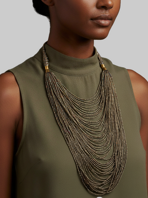 Woman wearing a long, layered necklace with a plain background