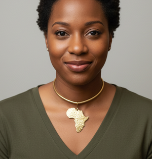 A woman wearing a gold necklace with an African map pendant against a neutral background 
