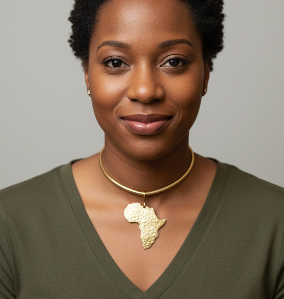 A woman wearing a gold necklace with an African map pendant against a neutral background 