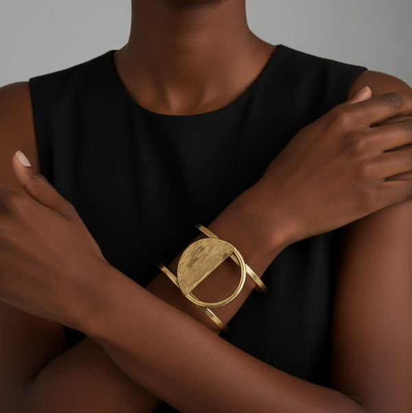 Person wearing a gold cuff on a neutral background