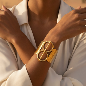 Gold bracelet on a wrist with a neutral background
