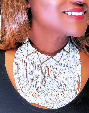 A close-up image of a person wearing a white beaded choker necklace with a geometric pattern and gold accents.